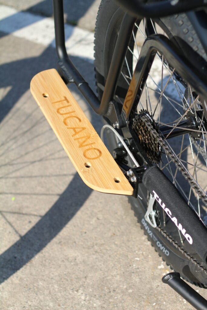 Joven sonriendo mientras pasea en una bicicleta eléctrica Tucano Bikes por la ciudad, reflejando el estilo de vida urbano.