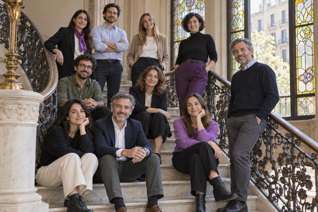 Equipo de diez personas de un despacho posando en dos alturas en una escalera modernista con vidrieras en Barcelona